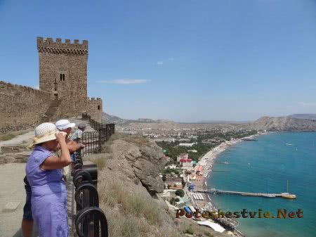 Туристы любуются на судакскую бухту со смотровой площадки крепости Туристы любуются на судакскую бухту со смотровой площадки крепости